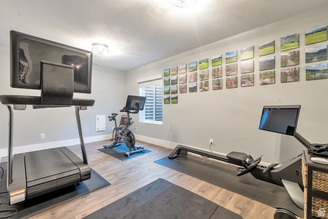 workout room featuring a textured ceiling, wood finished floors, and baseboards