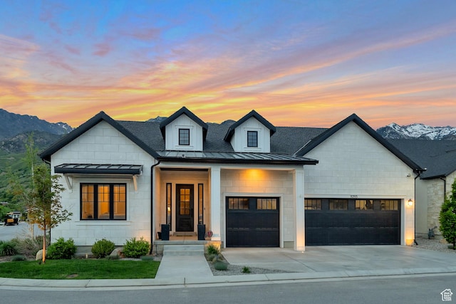 modern farmhouse with a standing seam roof, a garage, metal roof, a mountain view, and concrete driveway