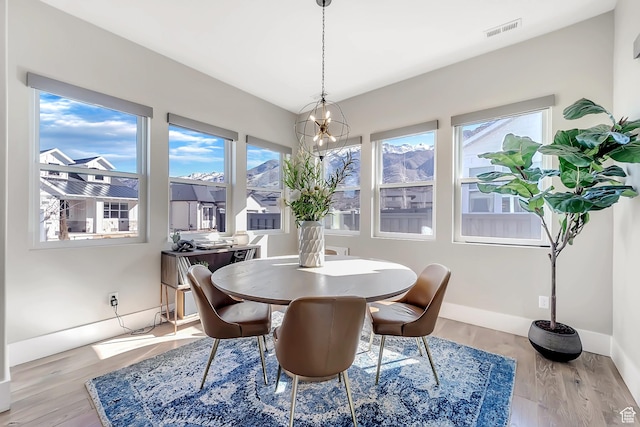 dining area with plenty of natural light, visible vents, an inviting chandelier, and wood finished floors