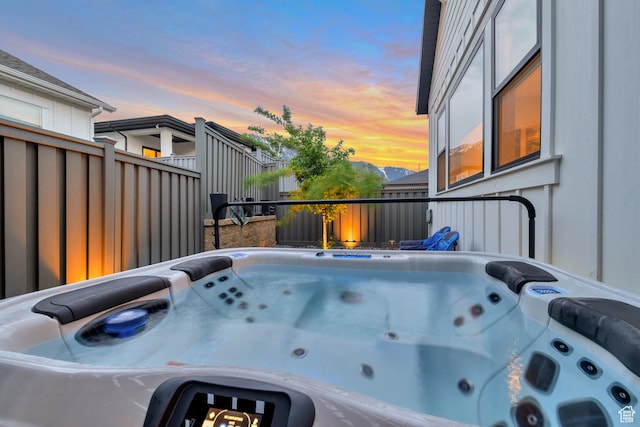 pool at dusk with a hot tub