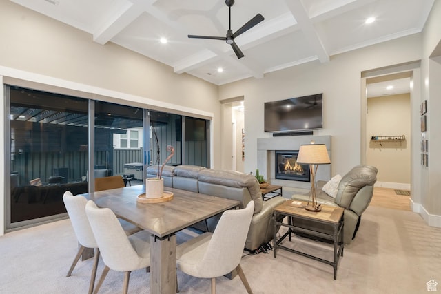 dining space with coffered ceiling, ceiling fan, beamed ceiling, and a glass covered fireplace