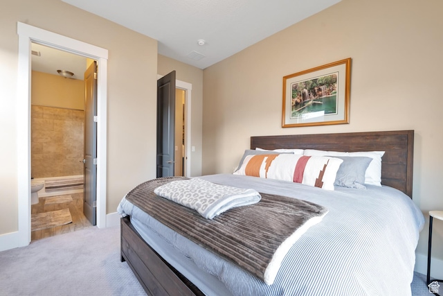 carpeted bedroom featuring baseboards and ensuite bath