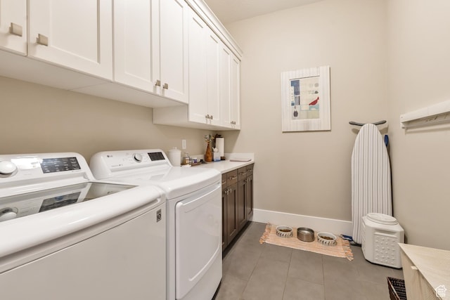 clothes washing area with light tile patterned flooring, baseboards, cabinet space, and washer and clothes dryer