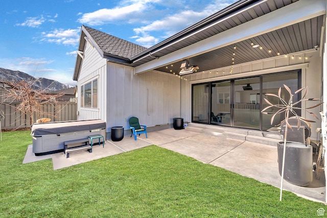 rear view of house featuring a yard, fence, a patio, and a hot tub