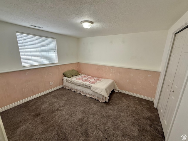 952 W 675 N, Tremonton, UT 84337 - unfurnished bedroom with wooden walls, a textured ceiling, and dark colored carpet