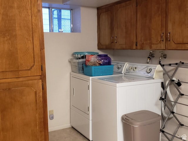clothes washing area featuring light tile patterned floors, baseboards, cabinet space, and washing machine and dryer