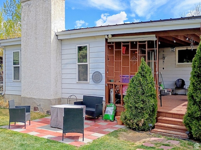 back of property with a deck, a chimney, and a patio