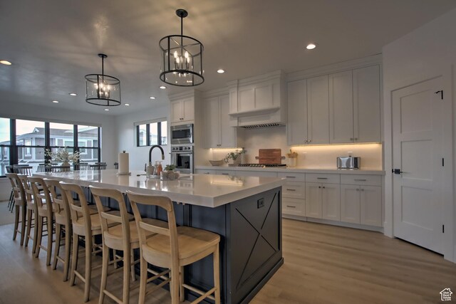 585 N Amber Ln, Garden City, UT 84028 - kitchen with pendant lighting, a notable chandelier, white cabinets, appliances with stainless steel finishes, and a large island