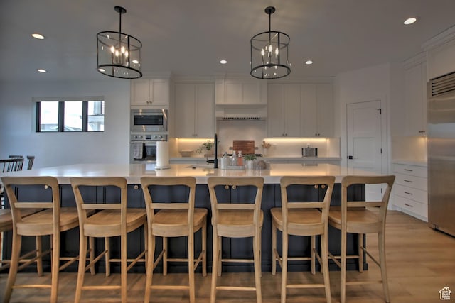 585 N Amber Ln, Garden City, UT 84028 - kitchen with appliances with stainless steel finishes, decorative light fixtures, a notable chandelier, white cabinetry, and a large island