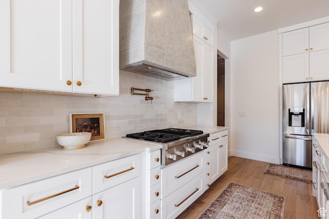 3305 W 2610 S, Hurricane, UT 84737 - kitchen featuring stainless steel appliances, white cabinets, light wood-type flooring, light stone countertops, and premium range hood
