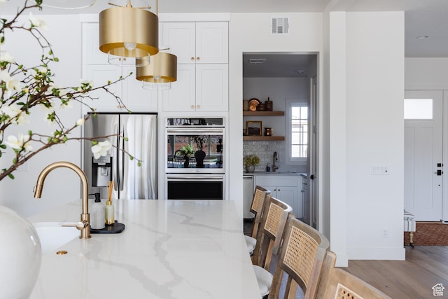 3305 W 2610 S, Hurricane, UT 84737 - kitchen with a sink, appliances with stainless steel finishes, white cabinets, visible vents, and light wood-style floors