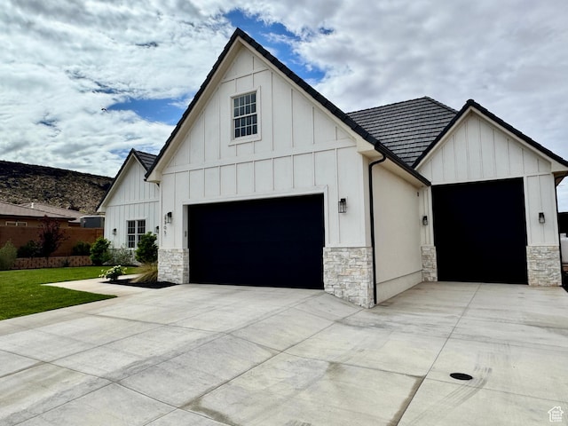 3305 W 2610 S, Hurricane, UT 84737 - view of side of home featuring an attached garage, stone siding, a lawn, concrete driveway, and board and batten siding