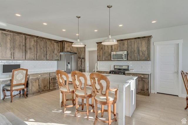 kitchen with appliances with stainless steel finishes, decorative backsplash, and light wood-type flooring