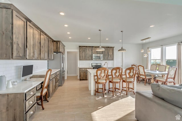 kitchen featuring appliances with stainless steel finishes, decorative backsplash, a breakfast bar, and recessed lighting