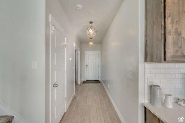 corridor with baseboards and light wood-style flooring