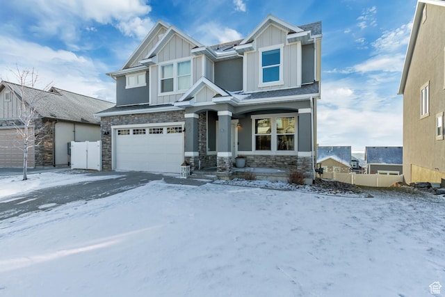 craftsman inspired home with a garage, board and batten siding, fence, and stone siding