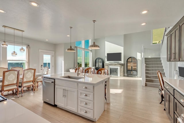 kitchen featuring light wood-type flooring, a sink, stainless steel dishwasher, and light countertops