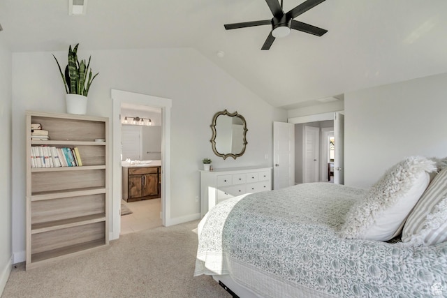 bedroom with light colored carpet, a ceiling fan, baseboards, ensuite bathroom, and vaulted ceiling