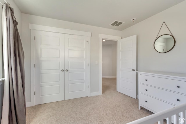 unfurnished bedroom with visible vents, baseboards, a closet, and light carpet