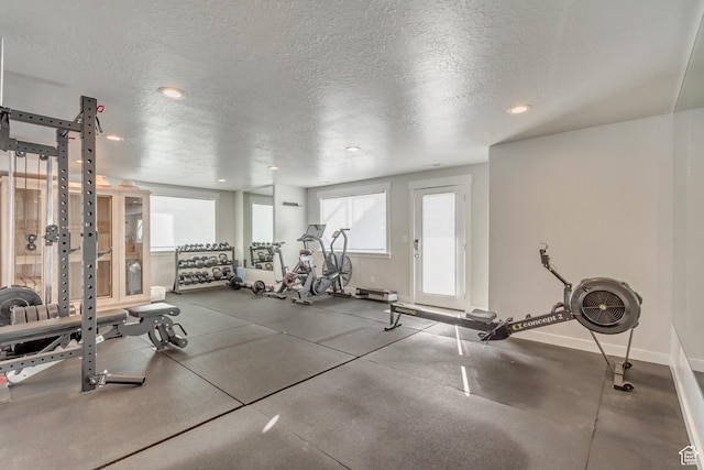 exercise room with baseboards, recessed lighting, and a textured ceiling