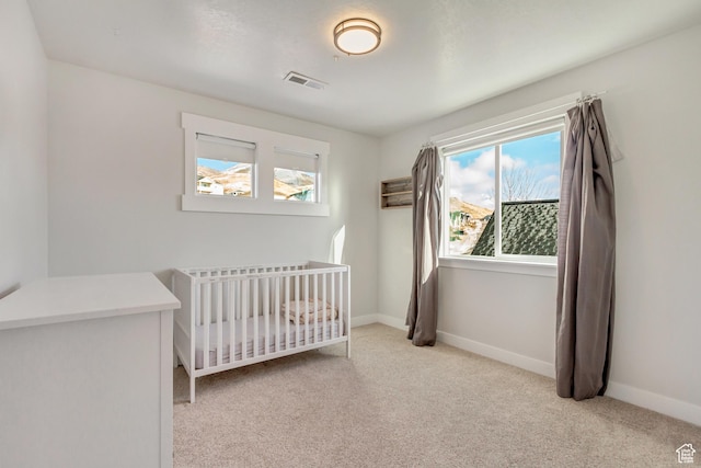 bedroom featuring carpet flooring, baseboards, visible vents, and a crib