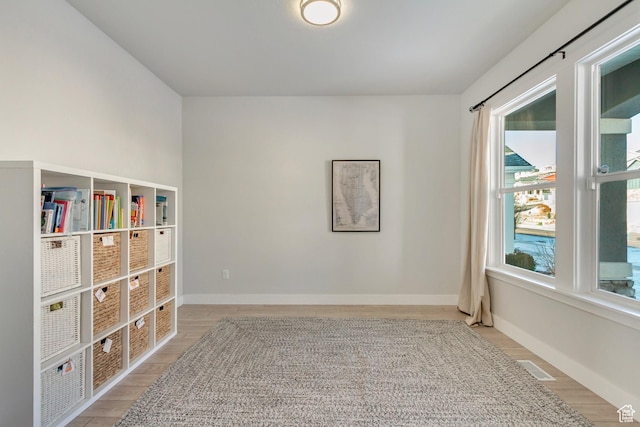 empty room featuring baseboards, a wealth of natural light, and light wood-style floors