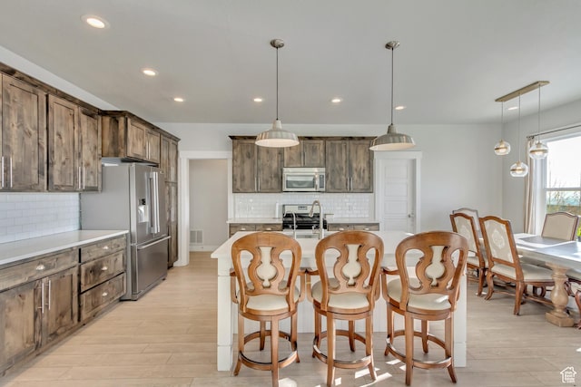 kitchen featuring stainless steel appliances, recessed lighting, tasteful backsplash, and light wood-type flooring