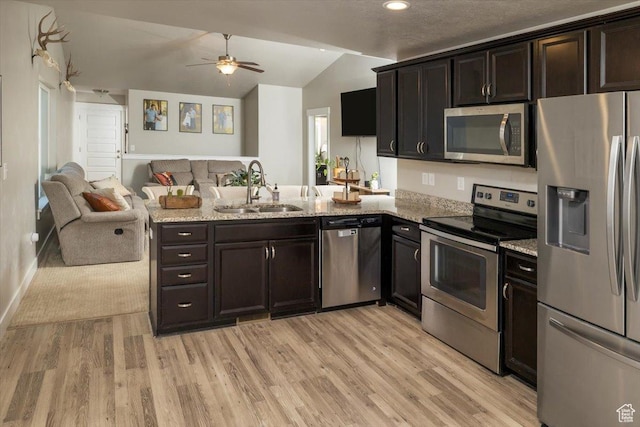 kitchen featuring kitchen peninsula, stainless steel appliances, sink, light hardwood / wood-style floors, and lofted ceiling