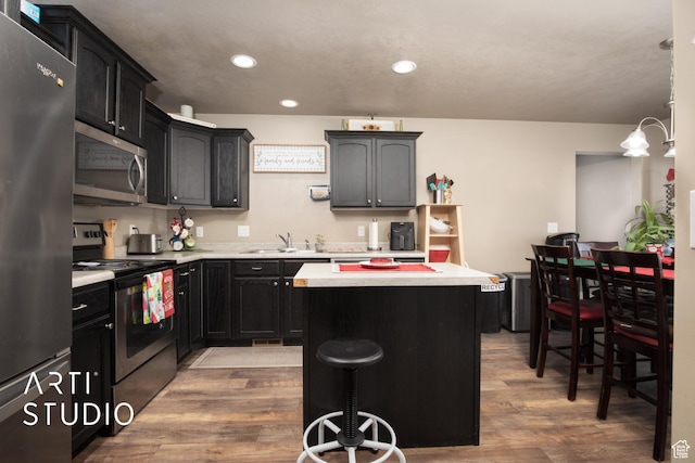 kitchen featuring a center island, dark wood-type flooring, appliances with stainless steel finishes, and a breakfast bar area