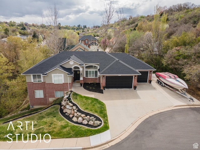 view of front of home with a shingled roof, concrete driveway, an attached garage, brick siding, and a front yard