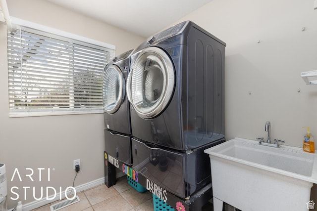 clothes washing area featuring a healthy amount of sunlight, a sink, laundry area, and light tile patterned floors