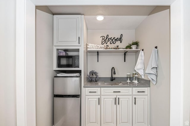 638 E Canyon Rim Rd N, Smithfield, UT 84335 - kitchen with black microwave, stainless steel counters, sink, white cabinetry, and stainless steel refrigerator