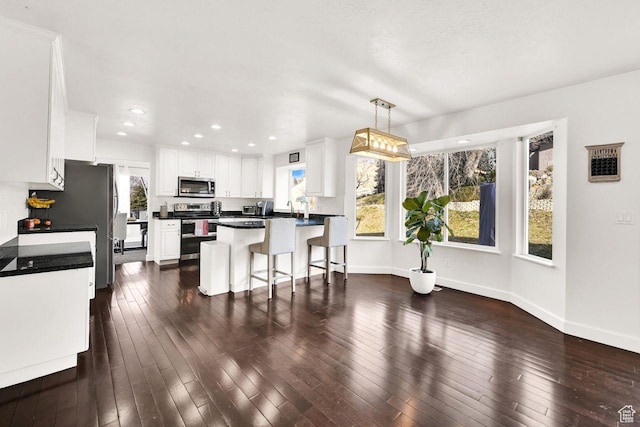 582 W 3900 N, Pleasant View, UT 84414 - kitchen with a kitchen breakfast bar, appliances with stainless steel finishes, decorative light fixtures, a kitchen island, and white cabinetry