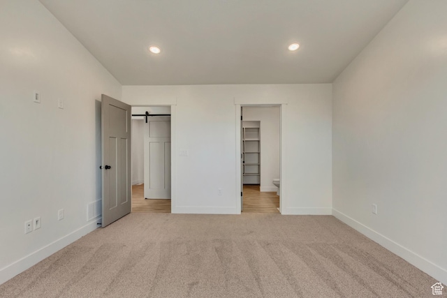 706 W Osborne Way S Unit 803, Grantsville, UT 84029 - unfurnished bedroom with a barn door, light colored carpet, a walk in closet, and a closet