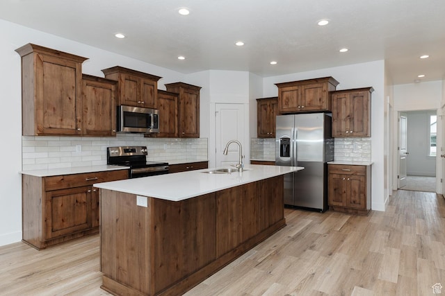 732 E 750 S, Preston, ID 83263 - kitchen with a sink, light wood-style floors, a center island with sink, backsplash, and stainless steel appliances
