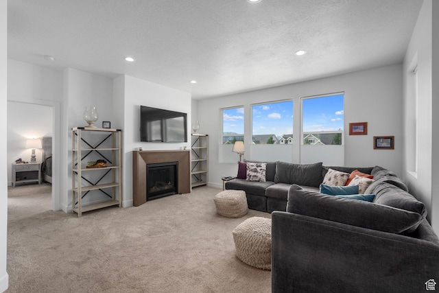 living room with a textured ceiling, baseboards, a glass covered fireplace, carpet flooring, and recessed lighting
