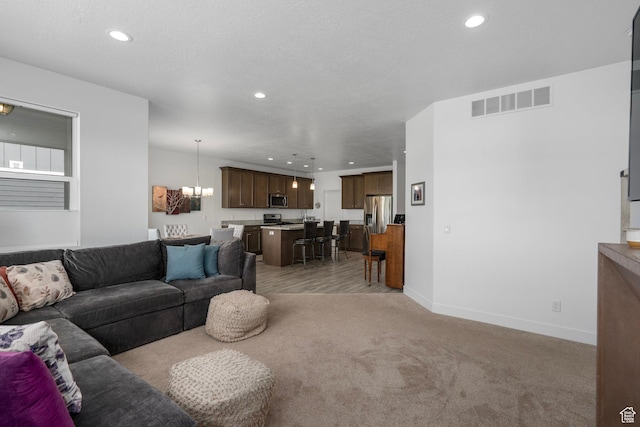 living room with visible vents, an inviting chandelier, baseboards, recessed lighting, and light colored carpet