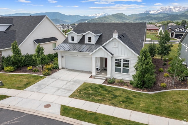 modern farmhouse with concrete driveway, board and batten siding, a mountain view, and a standing seam roof