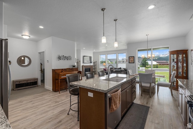 kitchen with a sink, light wood-style floors, stainless steel appliances, and a breakfast bar area