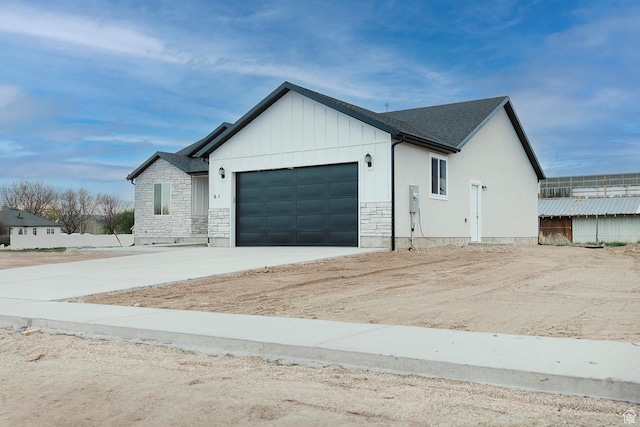 view of home's exterior with concrete driveway, an attached garage, stone siding, and board and batten siding