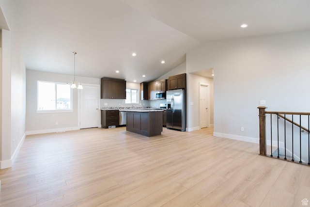 kitchen with dark brown cabinets, open floor plan, stainless steel appliances, light countertops, and a kitchen island