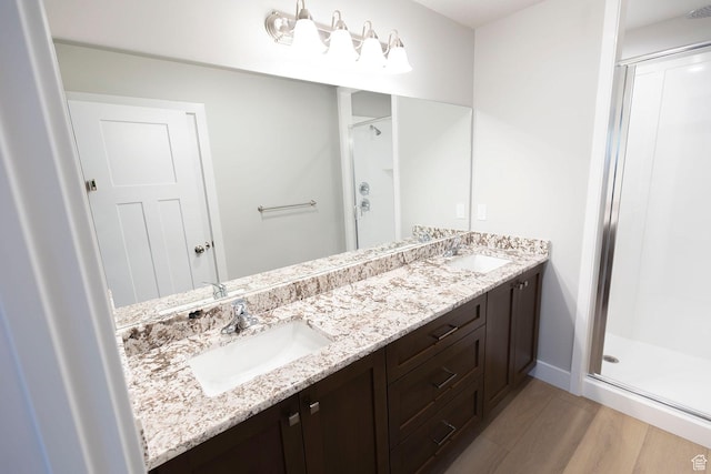 bathroom featuring a shower stall, wood finished floors, and a sink