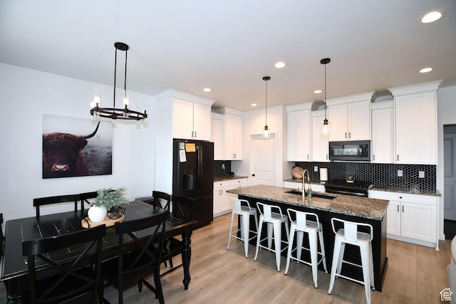 2129 N 3000 W, Plain City, UT 84404 - kitchen featuring white cabinetry, black appliances, a kitchen breakfast bar, and light wood finished floors