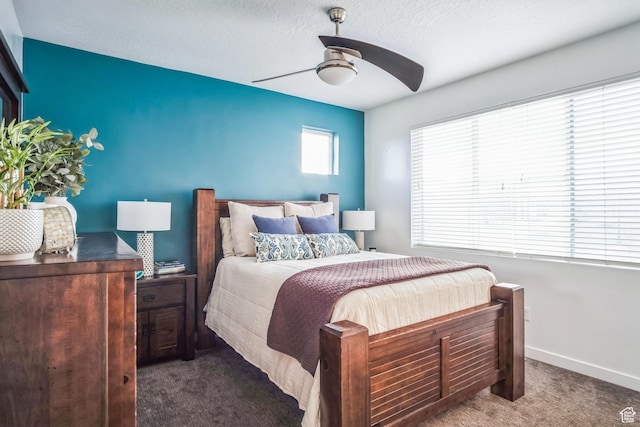 bedroom featuring ceiling fan, multiple windows, a textured ceiling, and dark carpet