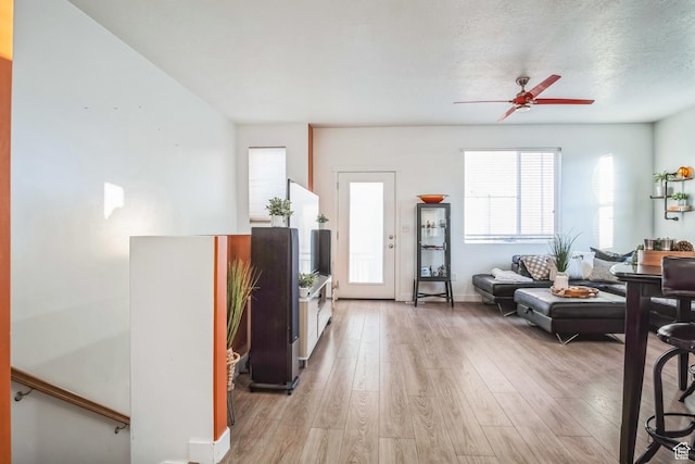 living room with a textured ceiling, ceiling fan, and light hardwood / wood-style floors