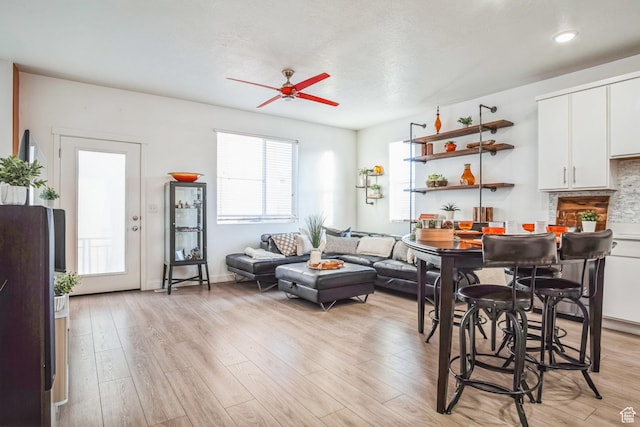 living room featuring a textured ceiling, ceiling fan, and light hardwood / wood-style floors