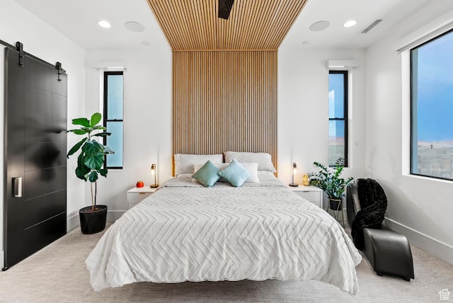 bedroom featuring a barn door, carpet floors, and multiple windows