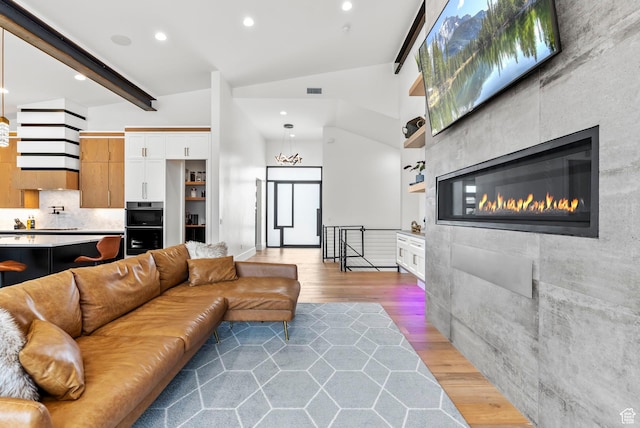 living room featuring vaulted ceiling with beams, wood-type flooring, and a fireplace