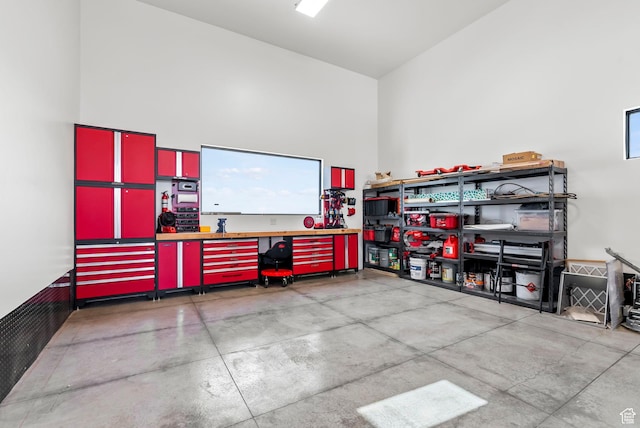 interior space with a workshop area, concrete flooring, and a towering ceiling