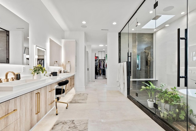 bathroom with a skylight, a shower with door, and vanity